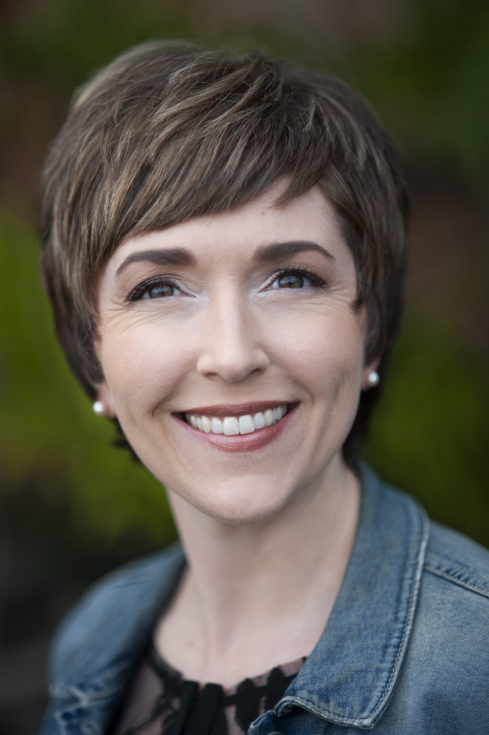 Head shot of the website owner showing her with short hair in a denim jacket